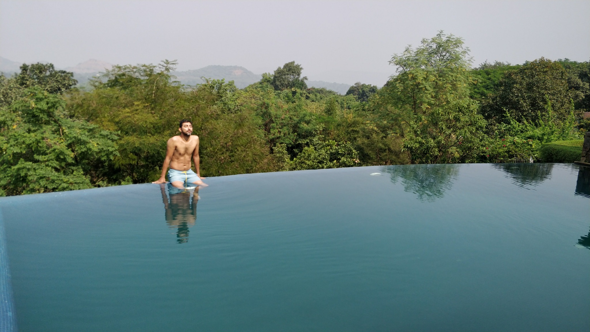 Guest sitting at the infinity pool overlooking rural Maharashtra